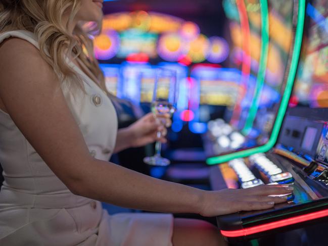 beautiful girl drinking wine alone at casino poker machine pokies istock generic