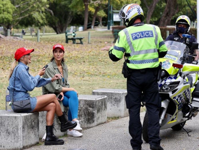 Police speak to unmasked women wearing “end lockdowns” caps in Brisbane's New Farm Park. Picture: Liam Kidston