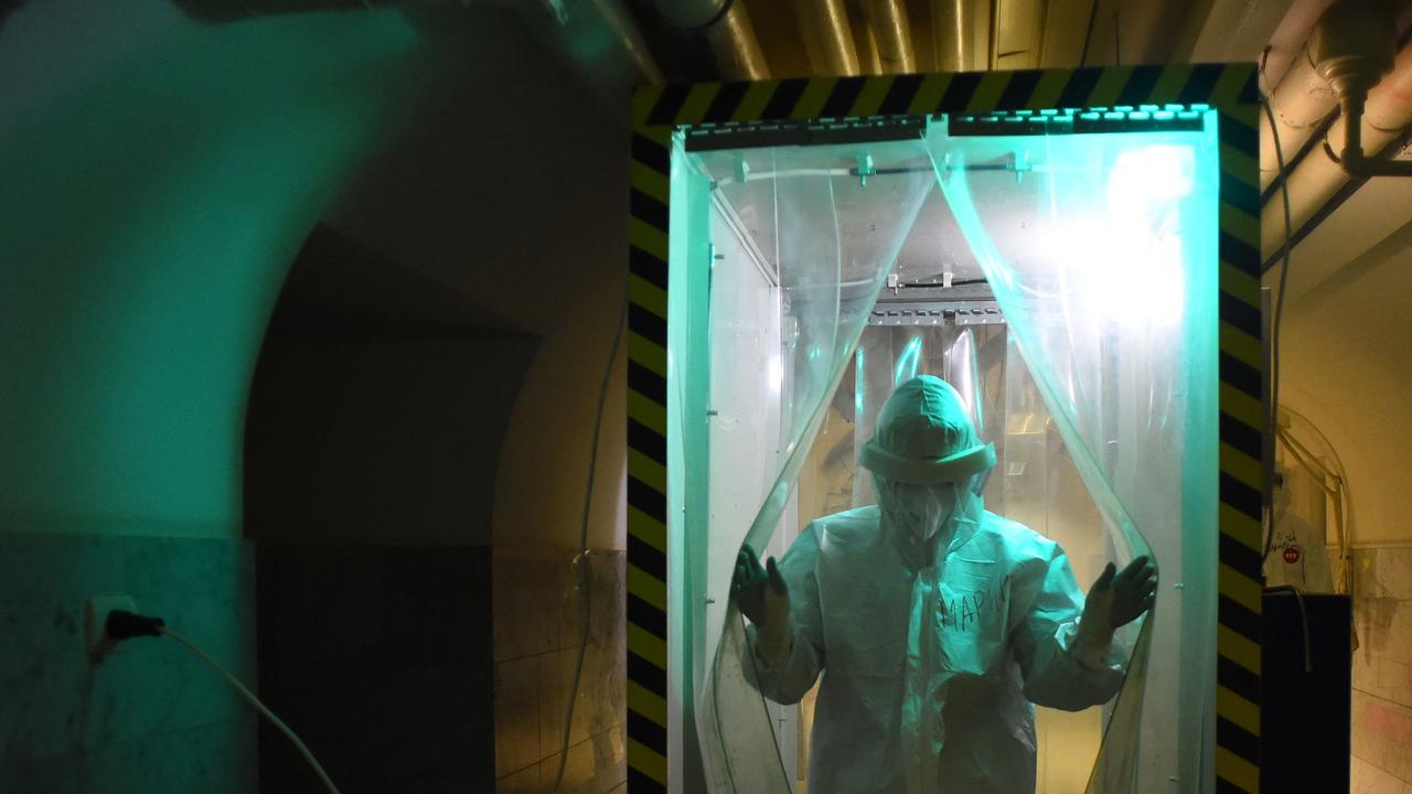 A medical worker wearing protective equipment walks through a disinfection cabin. Picture: AFP