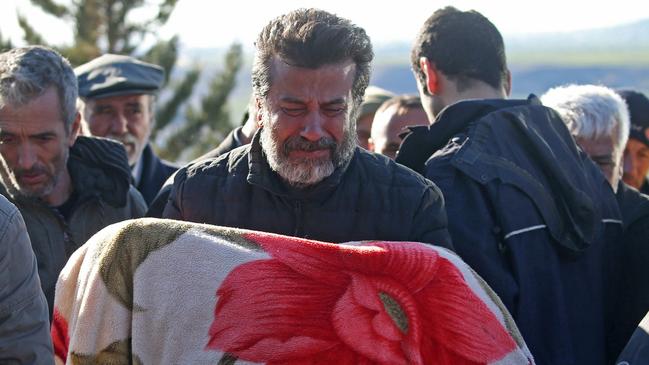 A man carries the body of child who was killed with his parents in a deadly earthquake, during a funeral in the village of Gozebasi in Adiyaman province, Turkey. Picture: REUTERS