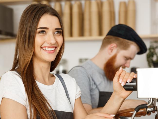 Coffee Business Concept - portrait of lady barista in apron preparing and steaming milk for coffee order with her partner while standing at cafe. Picture: iStock.