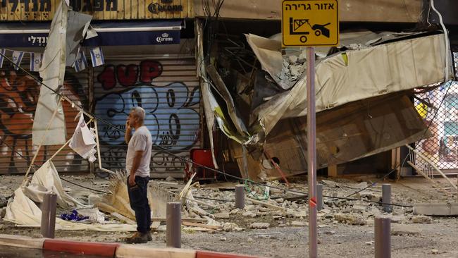 TOPSHOT - A man stands in front of a damaged shop in Tel Aviv, after it was hit by a rocket fired by Palestinian militants from the Gaza Strip on October 7, 2023. Palestinian militant group Hamas launched a surprise large-scale attack against Israel on October 7, firing thousands of rockets from Gaza and sending fighters to kill or abduct people as Israel retaliated with devastating air strikes. (Photo by JACK GUEZ / AFP)