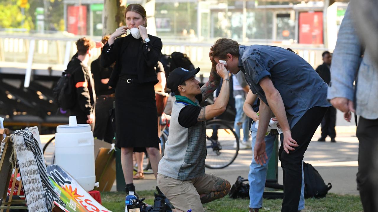 A cameraman (right) receives medical treatment from OC spray. Picture: James Ross/AAP