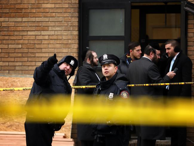 Police officers look at bullet holes in the windows of a school across the street from the JC Kosher Supermarket on December 11 in Jersey City, New Jersey. Six people, including a Jersey City police officer and three civilians were killed in a deadly, hours-long gunbattle between two armed suspects and police. Picture: AP