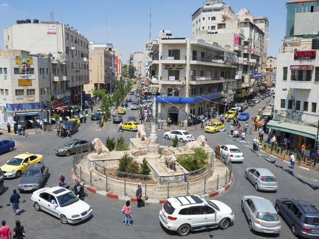 Traffic, pedestrians, and businesses at the Manara, the central traffic circle in downtown Ramallah. Located several miles north of Jerusalem, Ramallah is the seat of the Palestinian Authority government.