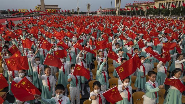 Chinese students wave party and national flags at a ceremony marking the 100th anniversary of the Communist Party at Tiananmen Square. Picture: Getty Images