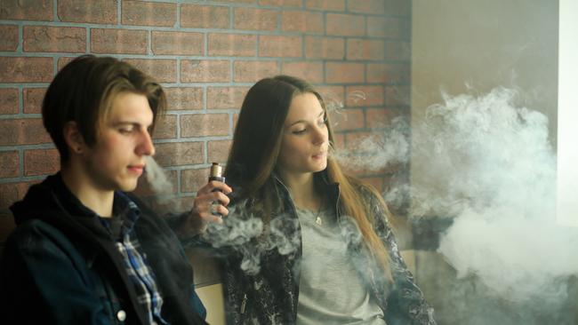 Teenagers smoke an electronic cigarette also known as vaping. File photo.