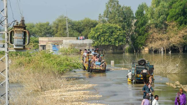 Internally displaced people use tractor trolley to wade across a flooded street in Dadu district of Sindh province, Pakistan. Photo by Asif Hassan.