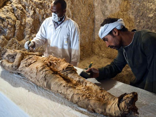 Egyptian archaeological technicians restore a mummy wrapped in linen, found at the newly discovered "Kampp 150" tomb at Draa Abul Naga necropolis on the west Nile bank of the southern Egyptian city of Luxor, about 650 kilometres (400 miles) south of the capital Cairo, on December 9, 2017. / AFP PHOTO / STRINGER