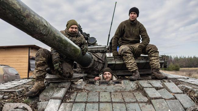 Ukrainian servicemen pose on a T-80 tank in an undisclosed location in eastern Ukraine.