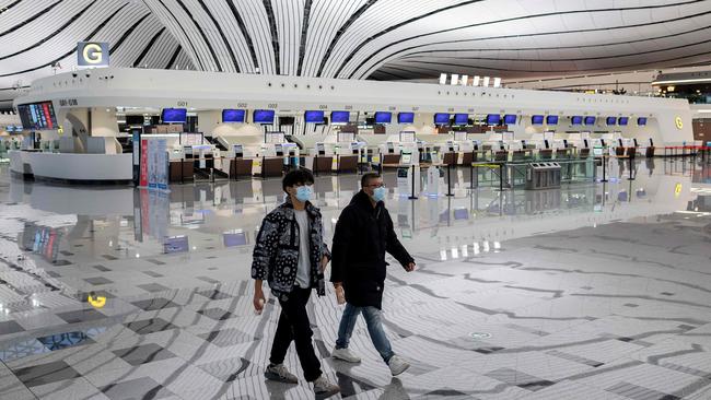 Two men wearing face masks walk through a nearly empty terminal at Daxing international airport in Beijing Picture: AFP