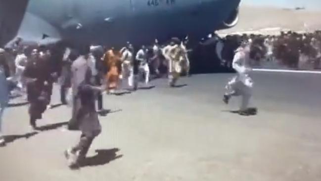 People stand in front of a US air force plane trying to leave.