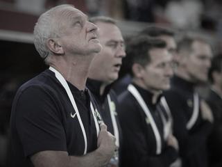 Australia's coach Graham Arnold (L) and his staff sing the national anthem ahead of the FIFA World Cup 2022 inter-confederation play-offs match between Australia and Peru on June 13, 2022, at the Ahmed bin Ali Stadium in the Qatari city of Ar-Rayyan. (Photo by MUSTAFA ABUMUNES / AFP)