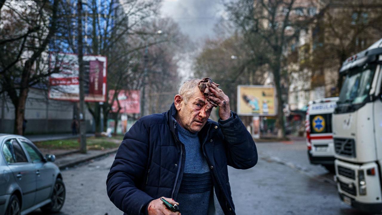 An injured man stands on a street after Russian shelling to Ukrainian city of Kherson on December 24, 2022. (Photo by Dimitar DILKOFF / AFP)