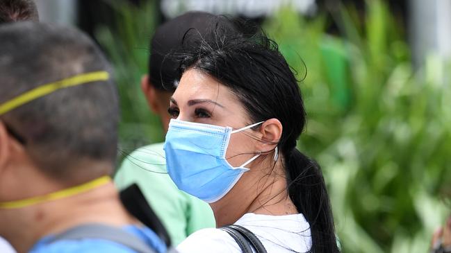 A woman wears a face mask in a long queue outside the Centrelink office in Southport on the Gold Coast earlier this year. It’s likely social distancing and other COVID-19 prevention measures have influenced the drop in flu cases and deaths. Picture: AAP Image/Dan Peled