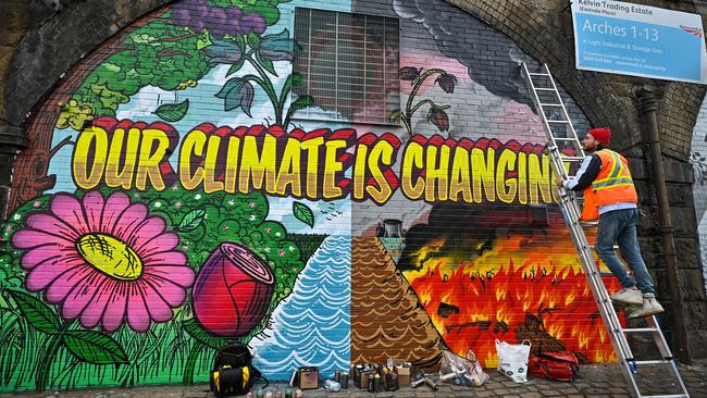 An artist paints a mural on a wall in Glasgow ahead of November’s COP26 summit. Picture: Getty Images