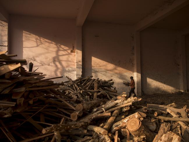 A worker carries logs of wood for funeral pyres at a crematorium in New Delhi, India. Picture: Getty Images