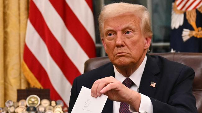 US President Donald Trump holds up outgoing President Joe Biden's letter as he signs executive orders in the Oval Office of the WHite House in Washington, DC, on January 20, 2025. (Photo by Jim WATSON / POOL / AFP) / ALTERNATE CROP