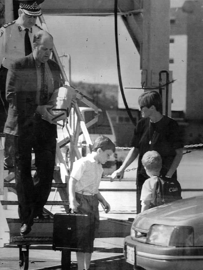 Matthew Bowen, aged 7, holds his father's monogrammed briefcase as he, his mother Jane and brother Simon, 5, arrive in Perth in 1994, after the bombing. Picture: Peter Ramshaw