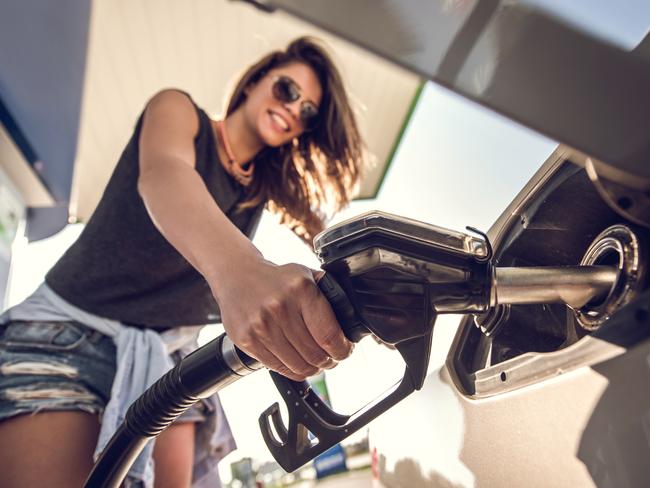 Close up of a woman refueling the petrol tank at fuel pump.