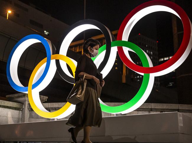 TOKYO, JAPAN - JULY 20: A woman wearing a face mask walks past the Olympic Rings on July 20, 2021 in Tokyo, Japan. With the Olympics now just a few days away, Tokyo is bracing itself for a Games without foreign fans or local attendance and a population enduring its fourth state of emergency amid the continuing global coronavirus pandemic. (Photo by Yuichi Yamazaki/Getty Images)