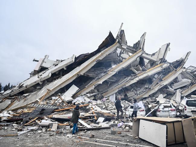 Survivors walk amongst a collapsed building in Hatay, Turkiye. Picture: Getty