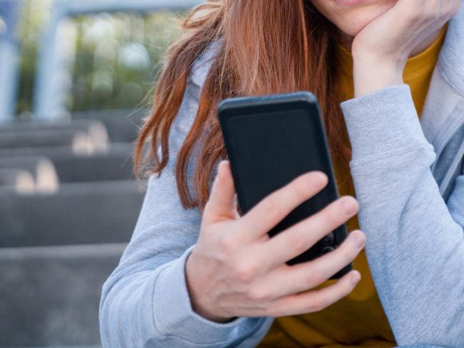 Worried young woman holding mobile phone waiting message