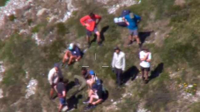 Missing hiker Hadi Nazari, 23 (seated) surrounded by hikers who located him off the circuit walk near Blue Lake. Picture: NSW RFS