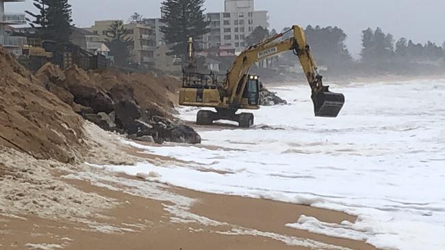 An excavator working to reinforce a temporary sand berm in front of homes on Collaroy/South Narrabeen Beach where part of a permanent sea wall is being built. The council will contribute $2.8m next financial year. Picture: Jim O'Rourke