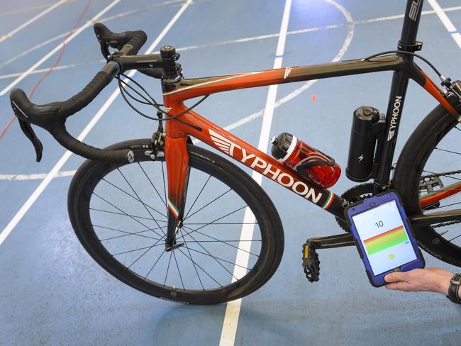 A staff member of the International Cycling Union (UCI) holds a tablet to scan a bicycle during a demonstation on testing technological fraud and detecting the presence of a motor inside the frame at the UCI headquarters in Aigle, western Switzerland, on May 3, 2016. The tablet scans a bicycle with magnetic resistance technology, testing the frame and wheels in less than a minute in order to detect mechanical doping during cycling races. / AFP PHOTO / FABRICE COFFRINI