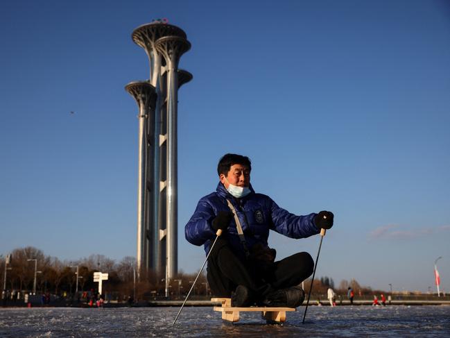 A man skates on a wooden sledge along a frozen canal near the closed loop "bubble" surrounding venues of the Beijing 2022 Winter Olympics in Beijing, China, January 25, 2022.   REUTERS/Thomas Peter