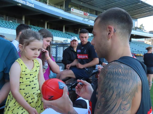 Collingwood player Jamie Elliott signs a football for Piper, four. Picture: Jon Tuxworth