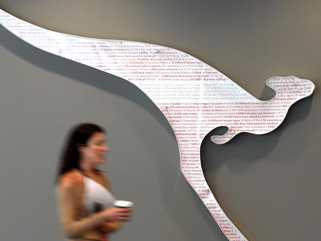 (FILES) In this file photo taken on November 1, 2019 a woman walks past the logo of Australia's national air carrier Qantas at the company's head office in Sydney on November 1, 2019. - Australia's Qantas is cutting 6,000 staff and grounding 100 planes for at least a year in a 10 billion USD cost-cutting blitz in response to the COVID crisis, the airline announced on June 25, 2020. (Photo by Saeed KHAN / AFP)