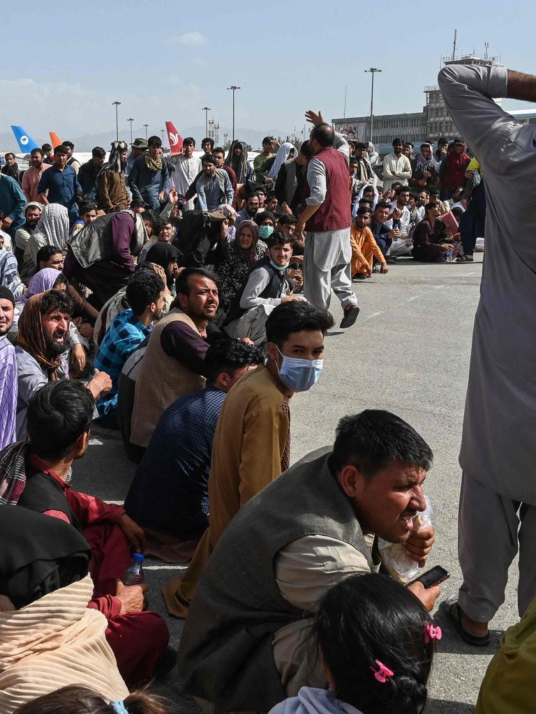 Afghans sit as they wait to leave the Kabul Airport on August 16, 2021. Picture: Wakil Kohsar/AFP