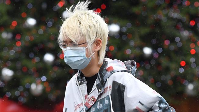 A woman wearing a protective face covering to combat the spread of the coronavirus, walks past a solitary Christmas Tree in a near-deserted Covent Garden in central London on November 19, 2020, as life under a second lockdown continues in England. - The current lockdown in England has shuttered restaurants, gyms and non-essential shops and services until December 2, with hopes business could resume in time for Christmas. (Photo by JUSTIN TALLIS / AFP)