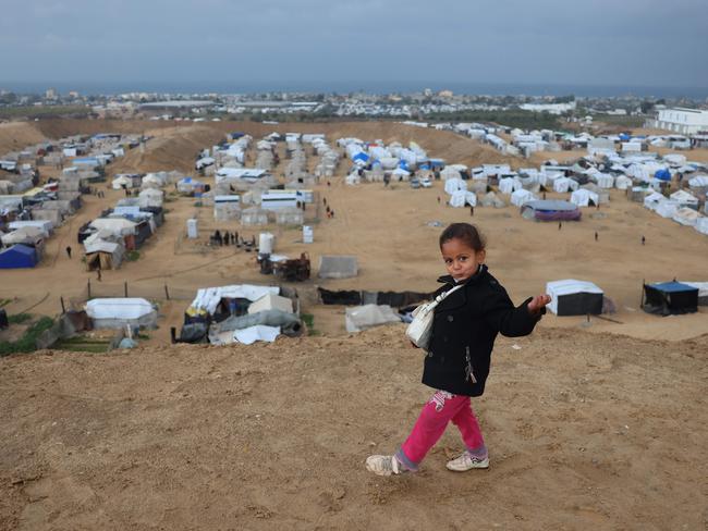 A displaced Palestinian girl poses for a picture as she walks next to a makeshift camp housing displaced Palestinians in Khan Yunis, in the southern Gaza Strip. Picture: AFP