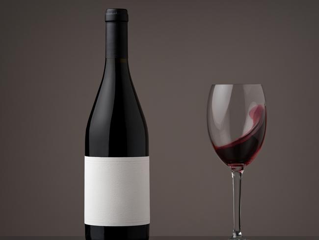 Wine bottle with wineglass. Red wine wave in a glass