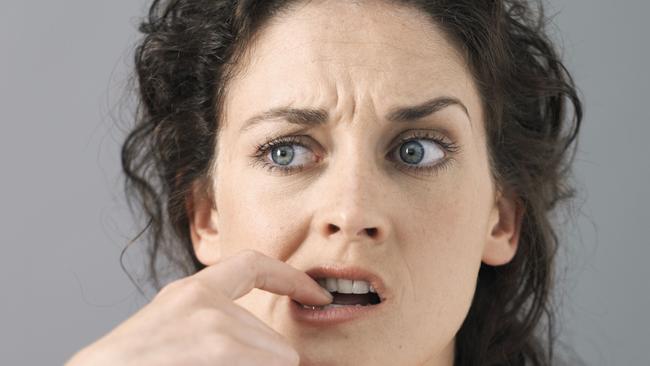 Young woman with finger in mouth, close-up, studio shot