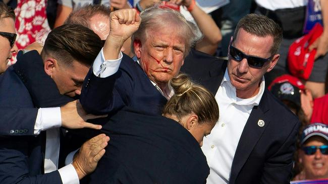 President Donald Trump pumps his fist as he is rushed offstage during a rally on July 13, 2024, in Butler, PA., alongside Secret Service agent Sean Curran. Picture: Rebecca Droke/AFP