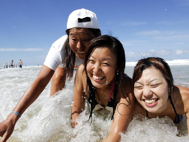 Gold Coast Beach Club, a GC Tourism initiative, introduces Japanese visitors to the beach. (L-R) member of the Beach Club crew Sayaka Umezawa teaches Japanese tourists Hiroko Enokida and Kayoko Taguchi the finer points of body surfing.