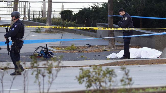 NYPD officers stands next to a body covered under a white sheet near a mangled bike along a bike path. Picture: AP