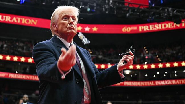 TOPSHOT - US President Donald Trump throws pens to the crowd after signing executive orders during the inaugural parade inside Capital One Arena, in Washington, DC, on January 20, 2025. (Photo by Jim WATSON / AFP)