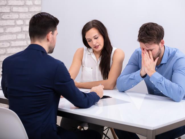 Rear View Of Financial Advisor Sitting With Depressed Young Couple