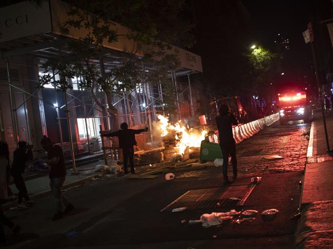 Protesters run down a street where a fire was started outside a Gucci store during a rally for George Floyd in New York. Picture: AP