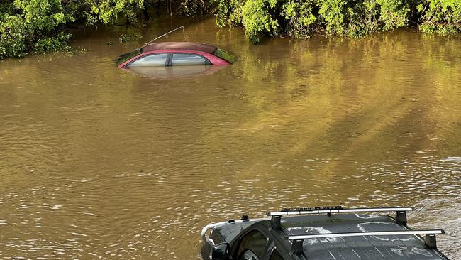 Cars parked near Nambour Plaza shopping centre were swallowed by rising flood waters from Petrie Creek.