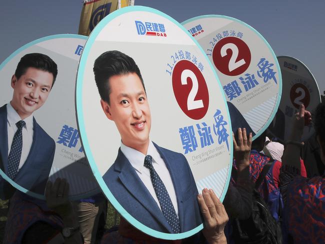 Supporters of Hong Kong pro-Beijing party Democratic Alliance for Betterment of Hong Kong (DAB) show their promotional posters of candidate Vincent Cheng Wing-shun during an election campaign for the upcoming district council elections in Hong Kong, Thursday, Nov. 21, 2019. The 2019 Hong Kong District Council elections are scheduled for Nov. 24. (AP Photo/Kin Cheung)