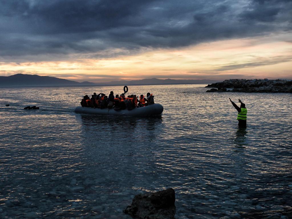 Refugees and migrants massed onto an inflatable boat reach Mytilene, northern island of Lesbos, after crossing the Aegean sea from Turkey on February 17, 2016. / AFP / ARIS MESSINIS