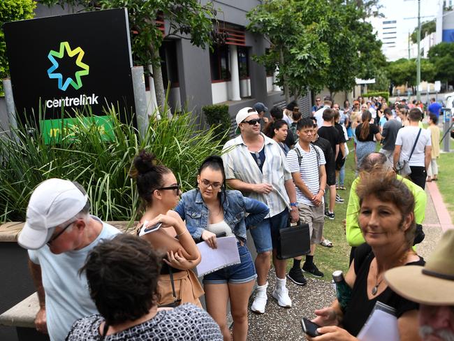 People are seen queueing outside the Centrelink office in Southport on the Gold Coast, Monday, March 23, 2020. Centrelink offices around Australia have been inundated with people attempting to register for the Jobseeker allowance in the wake of business closures due to the COVID-19 pandemic.  (AAP Image/Dan Peled) NO ARCHIVING