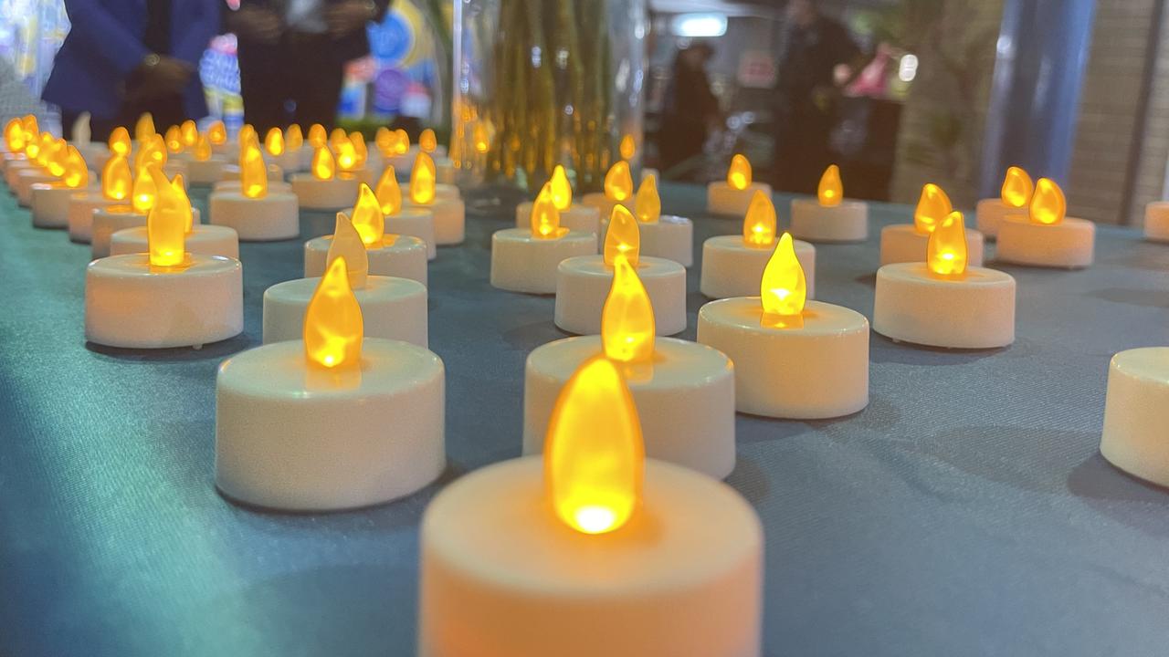 Members of the public placed candles on a table as the names were announced of women and children ranging in age from 10 months to 65 years who have been killed by domestic and family violence in 2023.