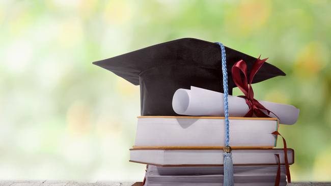 Graduation hat with degree paper on a stack of book against blurred background